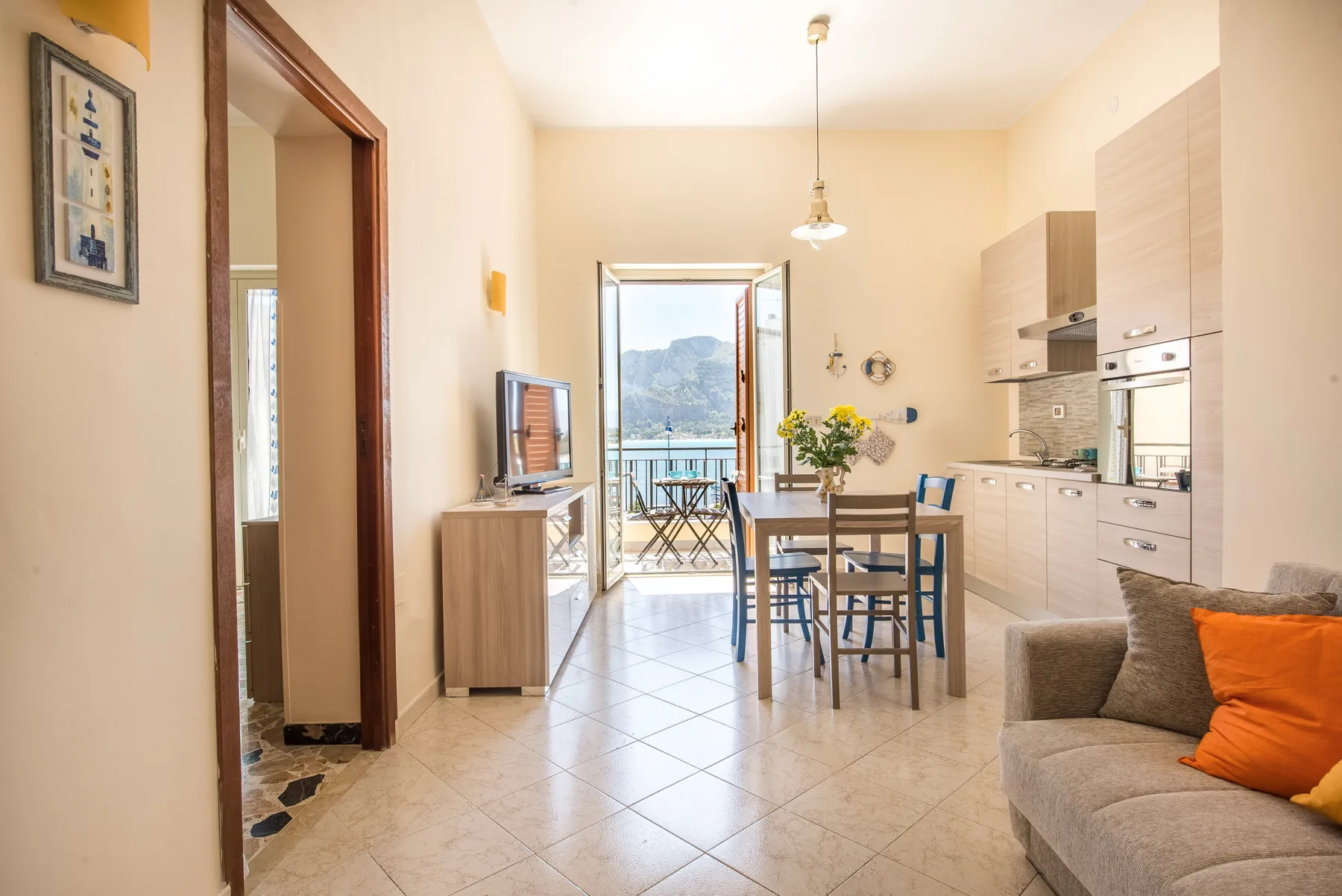 A bright open-plan dining and kitchen area with a table beside a balcony.