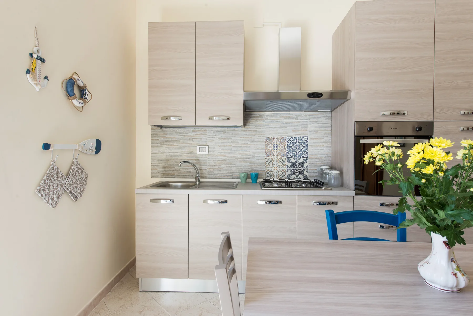 A kitchen with light cabinets and a dining table in the foreground.