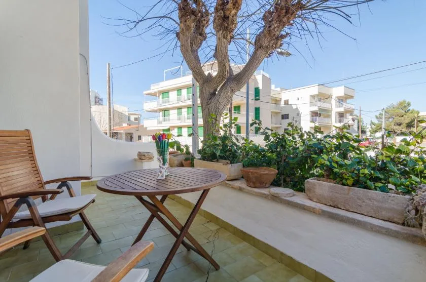 A patio seating area with a round table, chairs, and potted greenery.