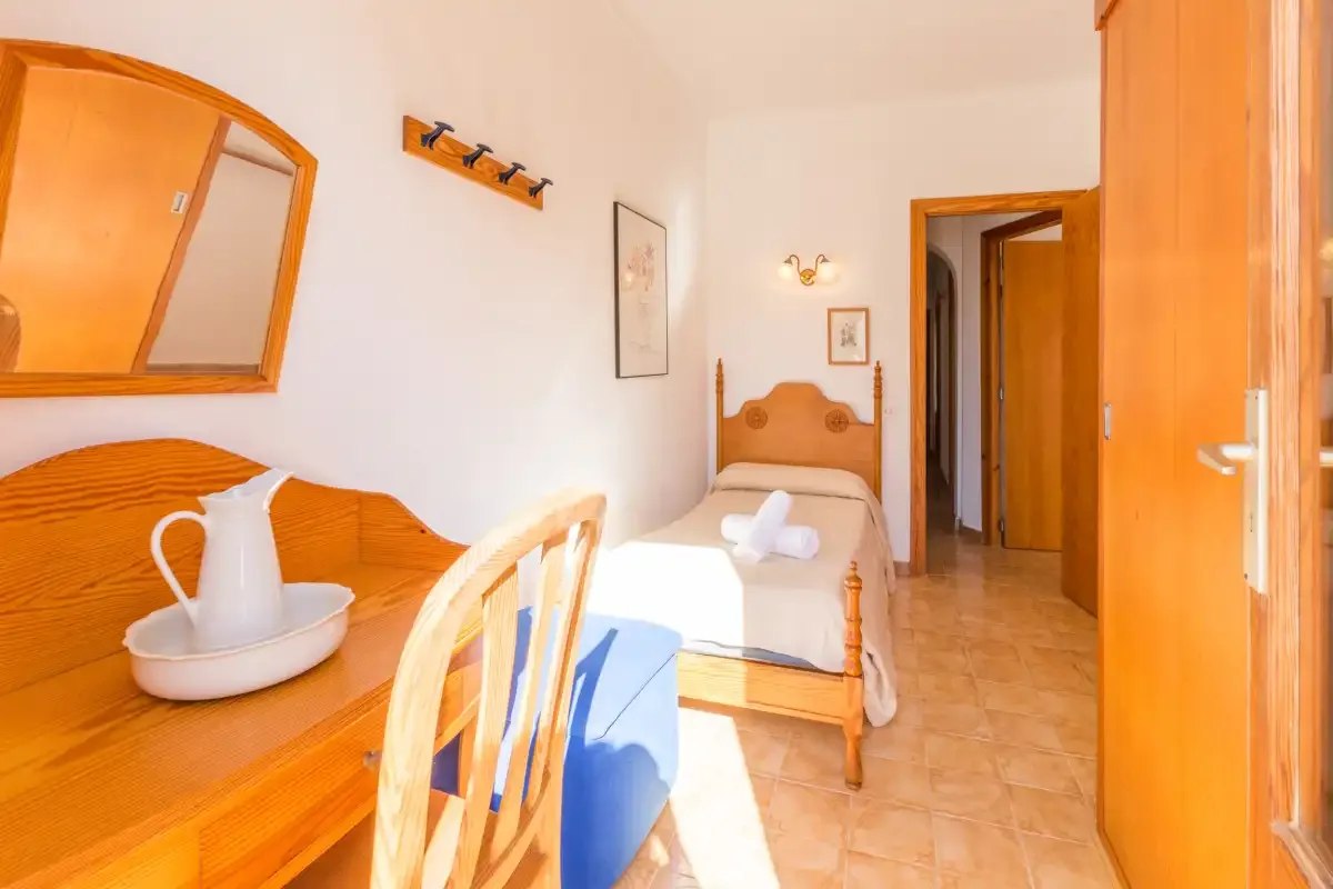 Un dormitorio luminoso con una cama de madera y un escritorio.