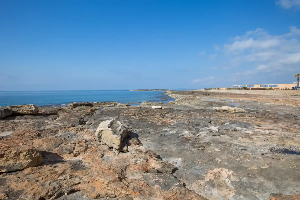 Una costa rocosa se extiende junto al mar azul bajo un cielo despejado.