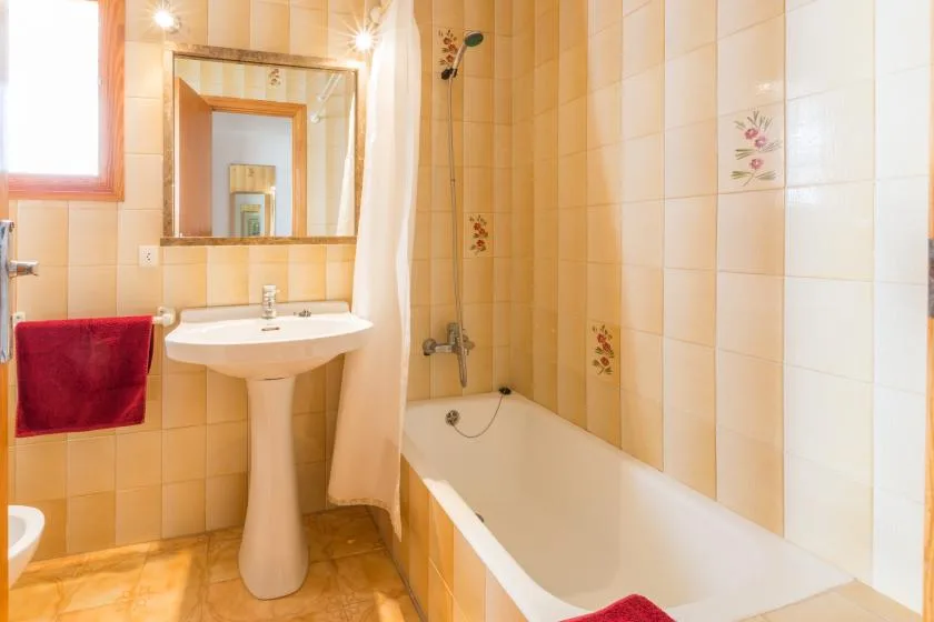 Un baño alicatado con bañera, lavabo y espejo.