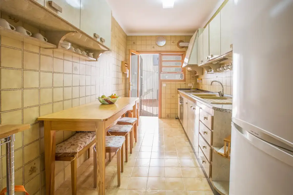 Una cocina estrecha con una mesa de madera y una encimera junto a la pared.
