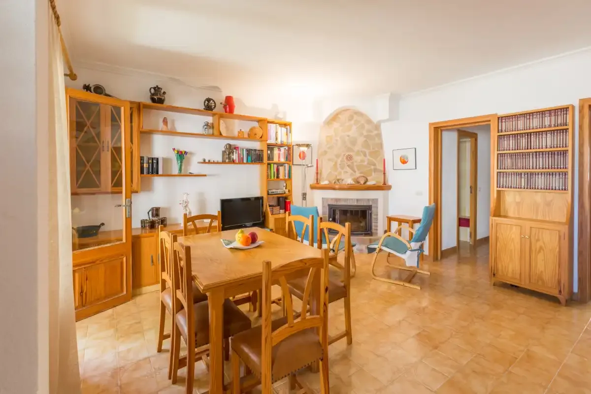 Comedor con una mesa de madera y asientos junto a una chimenea.
