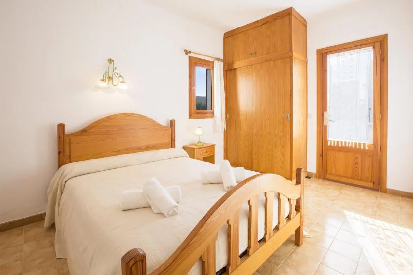 Un dormitorio luminoso con una cama de madera y un armario alto.