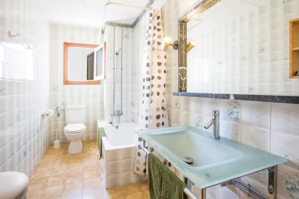 Un baño luminoso con bañera, lavabo e inodoro.