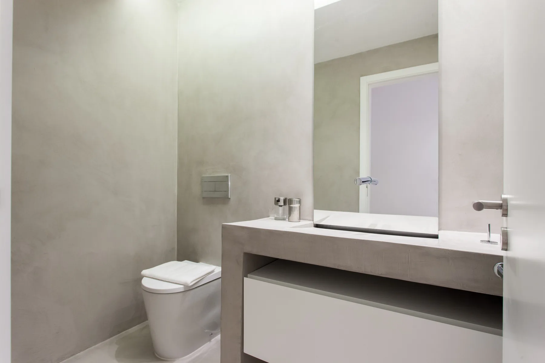 A bathroom with a toilet and a wide vanity beneath a mirror.
