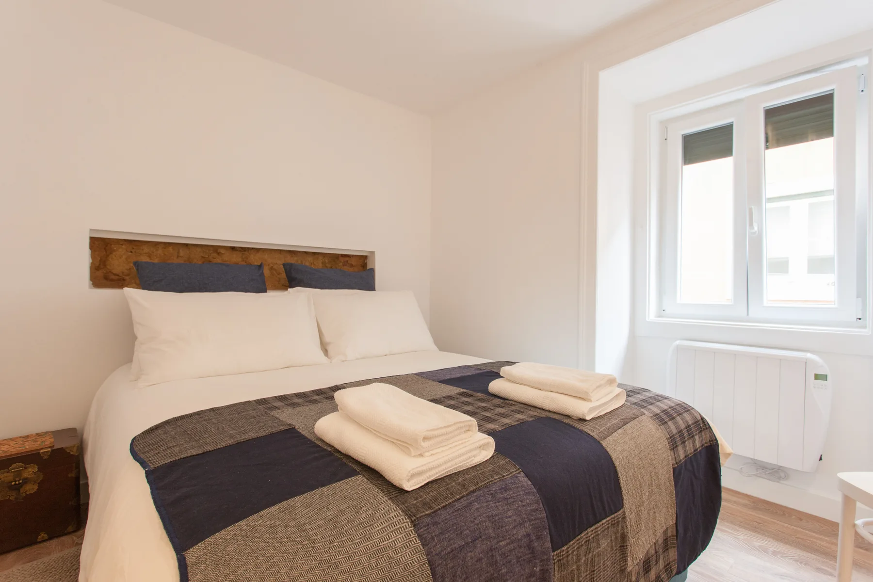A bedroom with a neatly made bed and a bright window.