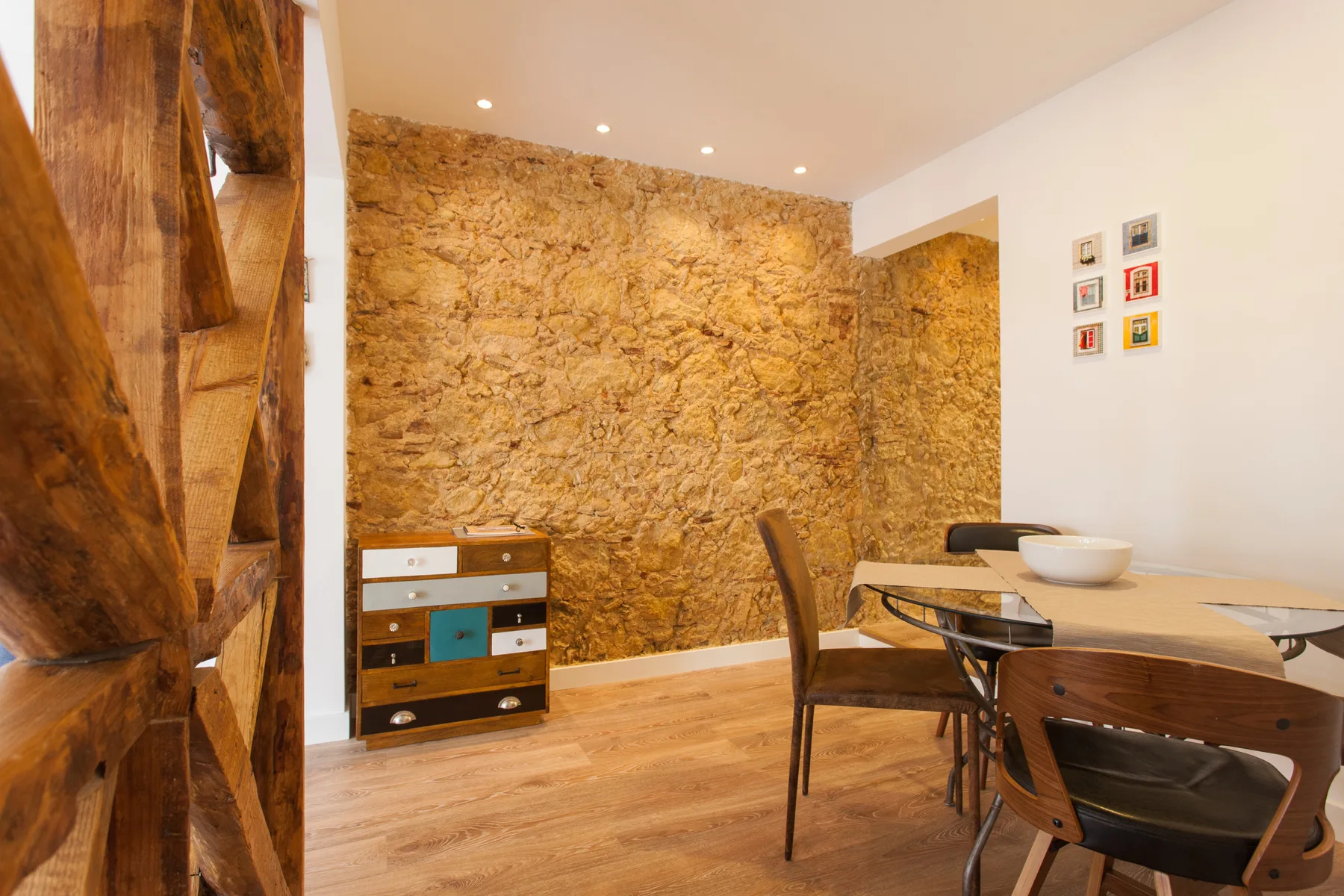 Dining area with a wooden table and chairs beside an exposed stone wall.