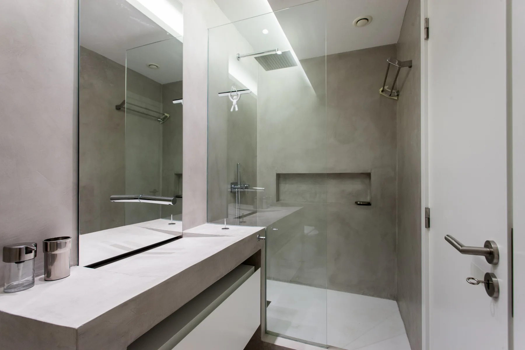 A modern bathroom with a glass shower and a long vanity.