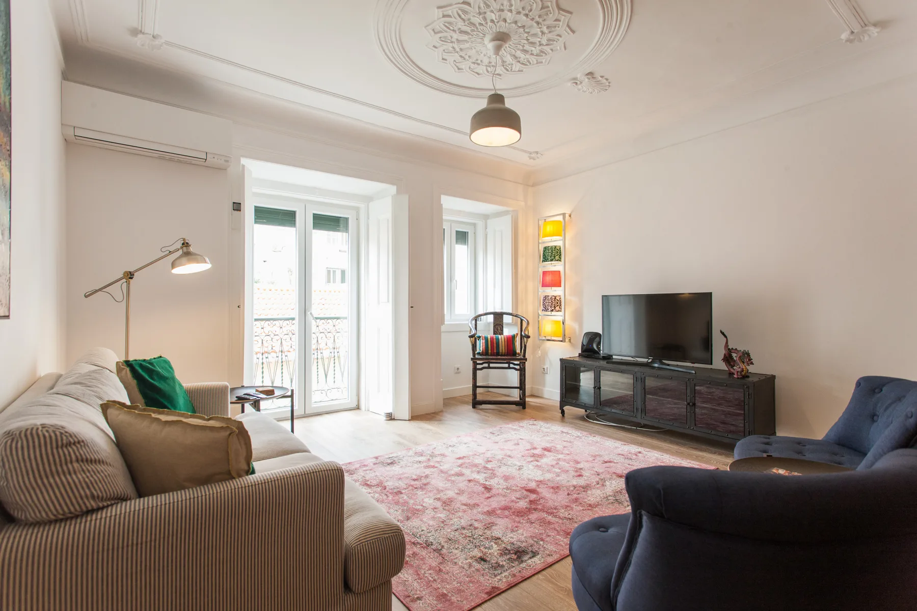 Living room with seating, a television, and tall windows.