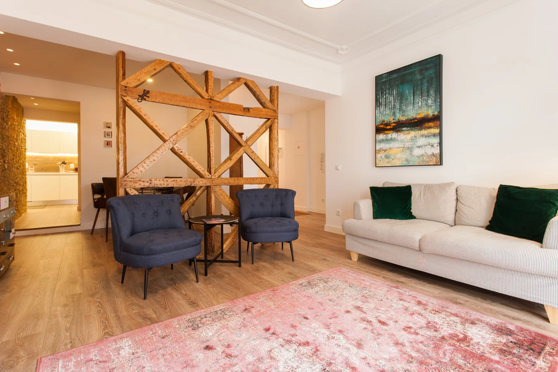 Living room with seating, a wooden divider, and a large area rug.