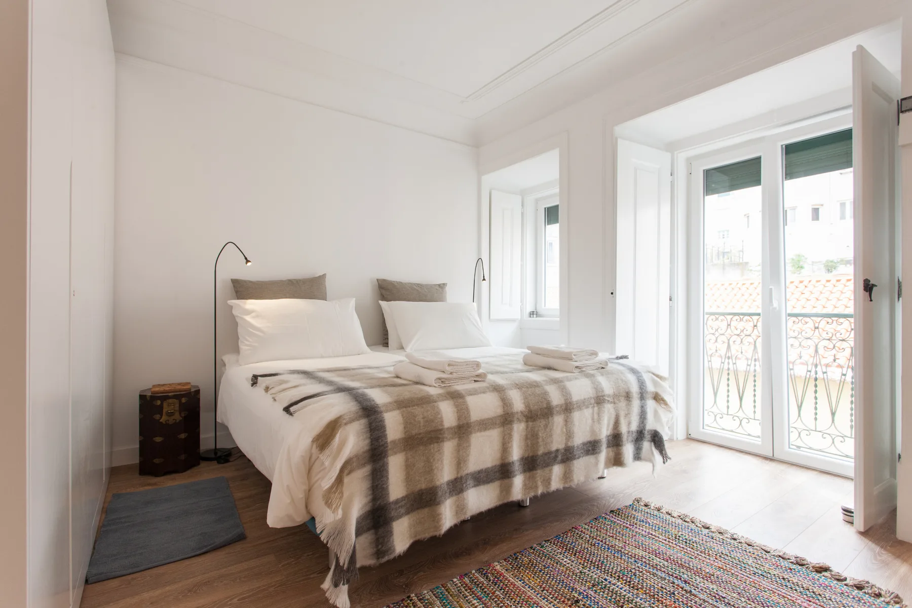 A bright bedroom with a double bed and glass doors opening onto a balcony.