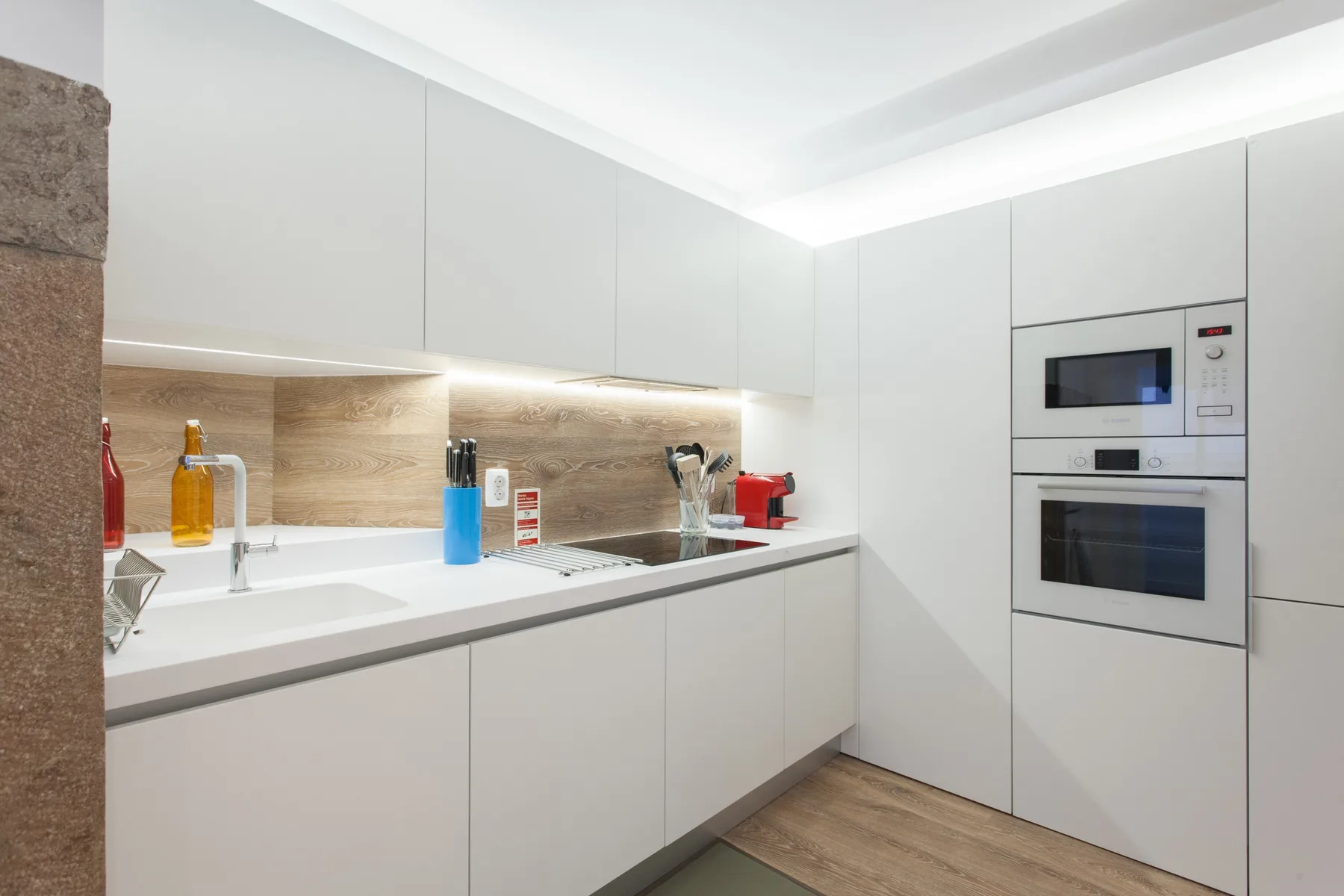A modern kitchen with white cabinets, a countertop, and built-in appliances.