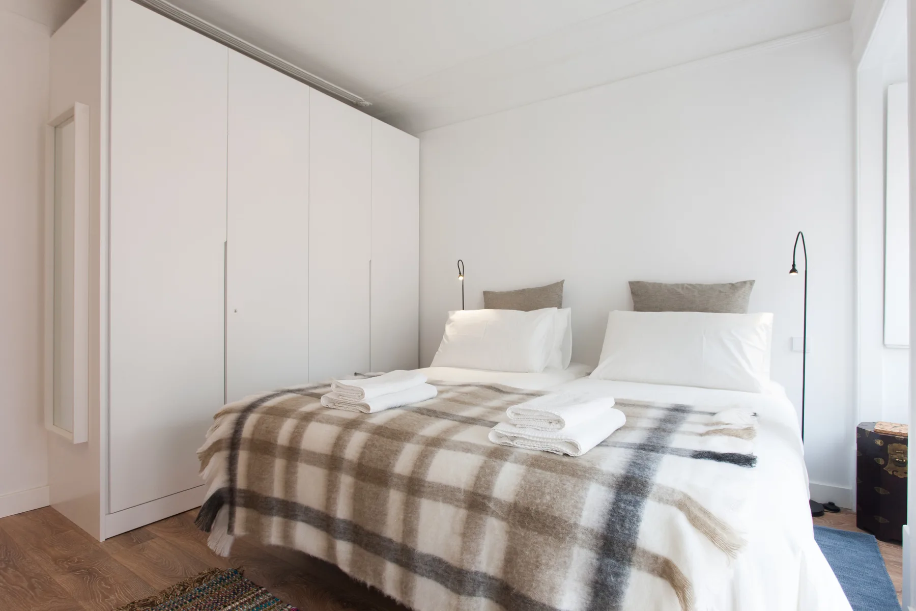 A bedroom with a double bed covered by a checkered blanket.