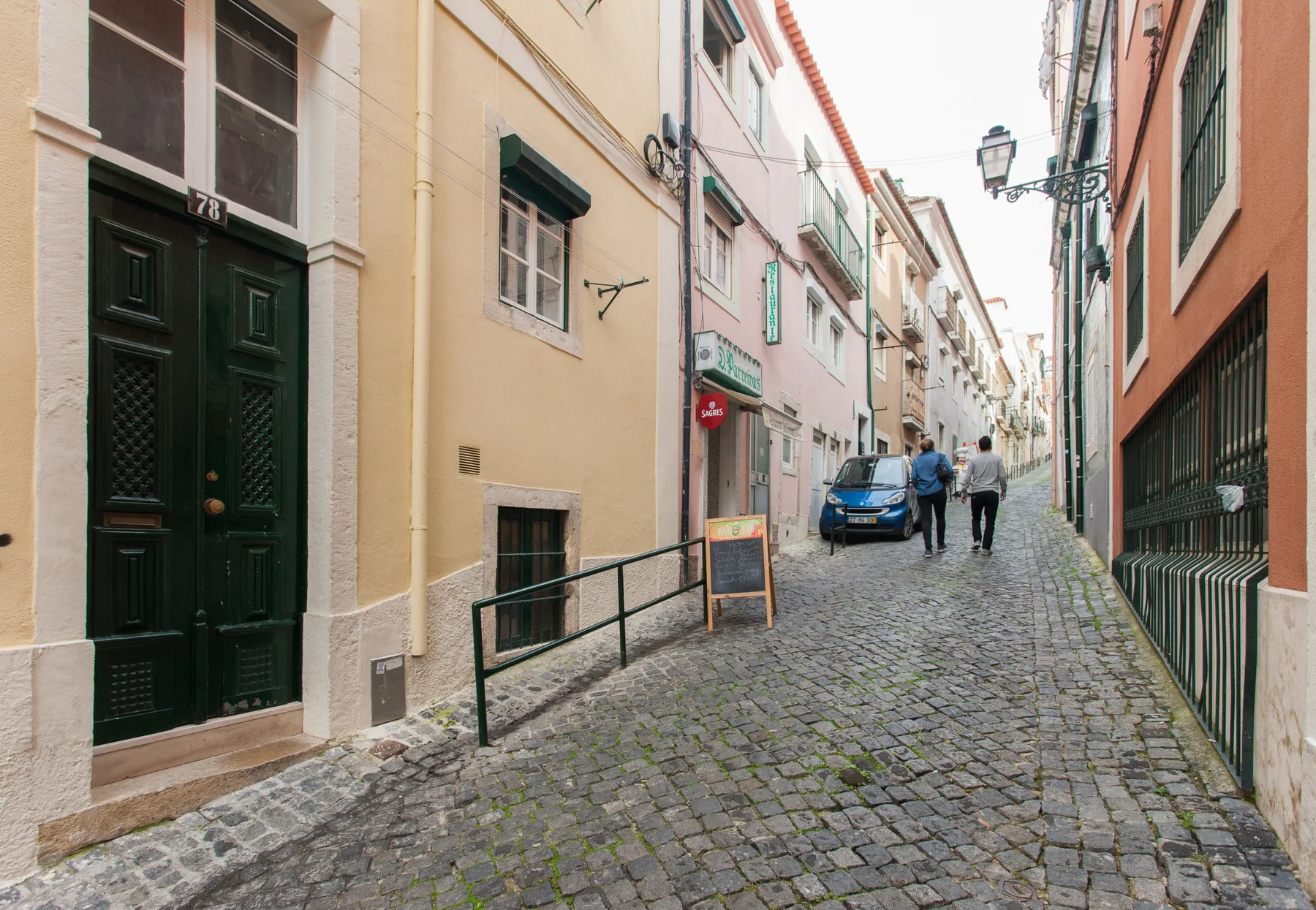 A narrow cobblestone street runs between closely spaced buildings.