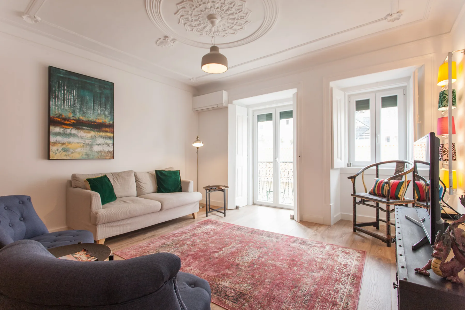 Living room with seating, a patterned rug, and tall windows.