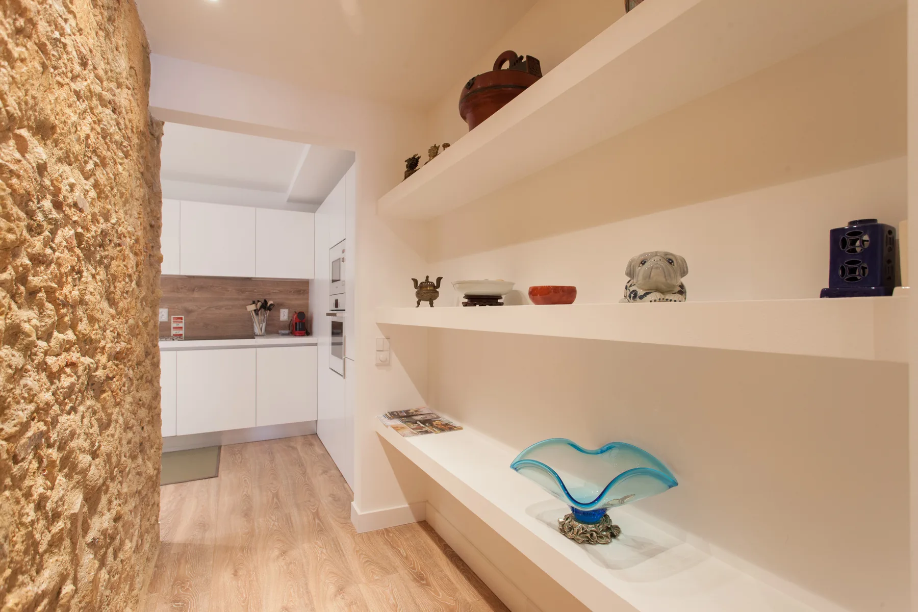 A kitchen with white cabinets and open display shelves along the wall.