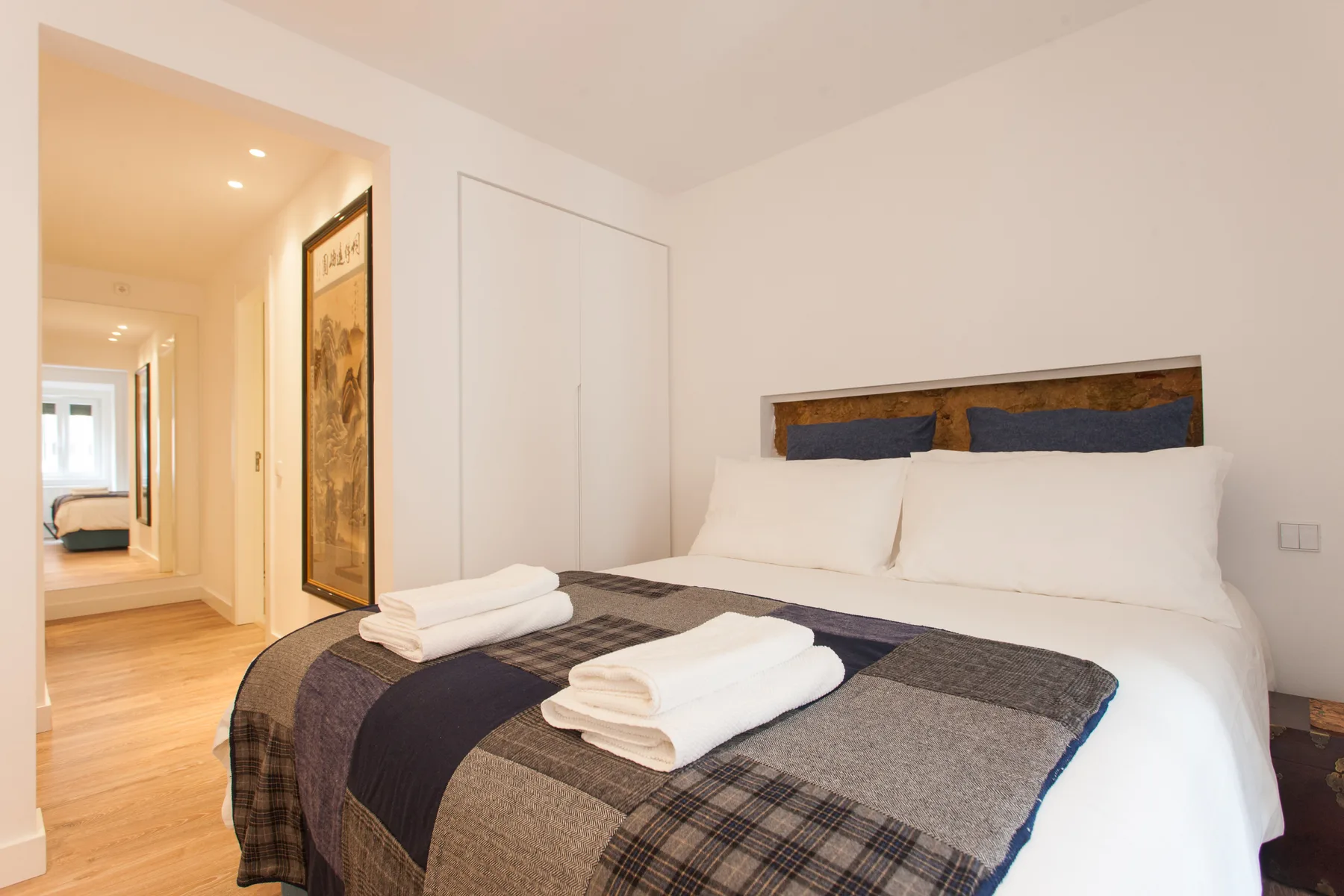 A bedroom with a neatly made bed and folded towels.