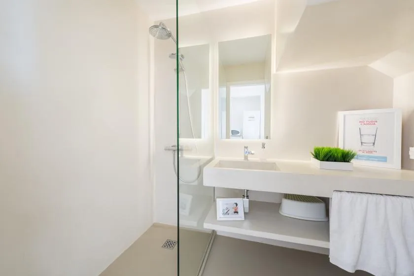 A bright bathroom with a glass shower and a long sink counter.