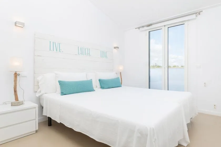 A bright bedroom with a neatly made bed and sliding glass doors.