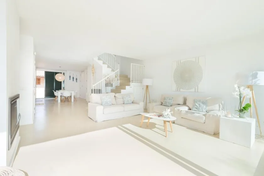 A bright living room with seating, a coffee table, and a staircase.