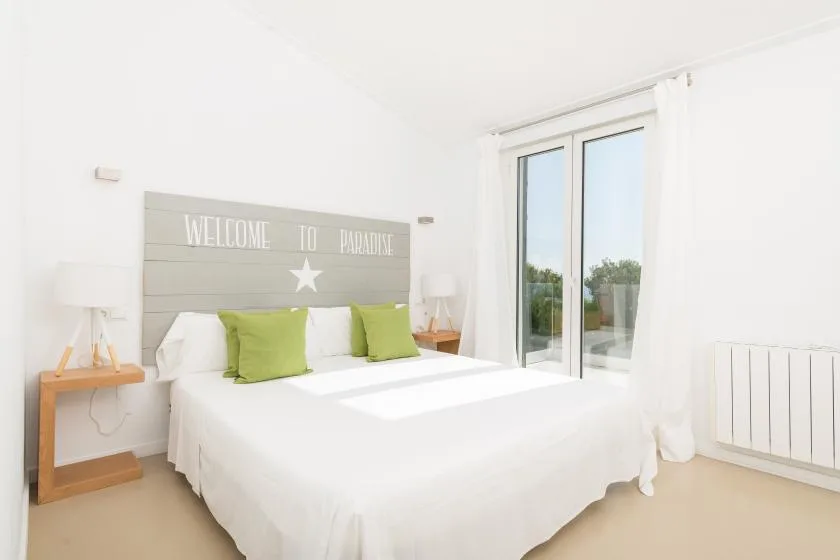 A bright bedroom with a neatly made bed and sliding glass doors.