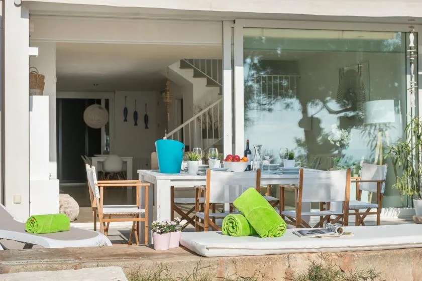 A patio dining area with a table and chairs beside large sliding glass doors.