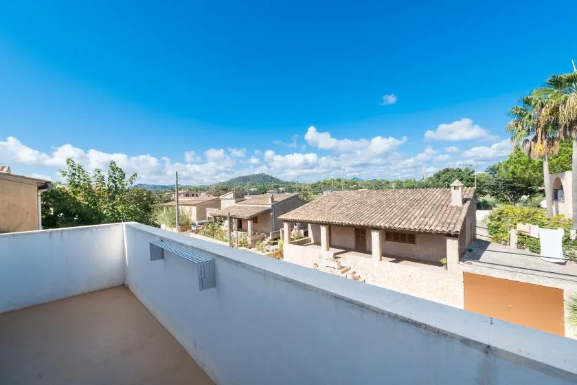 A sunny terrace overlooks nearby homes and distant hills.
