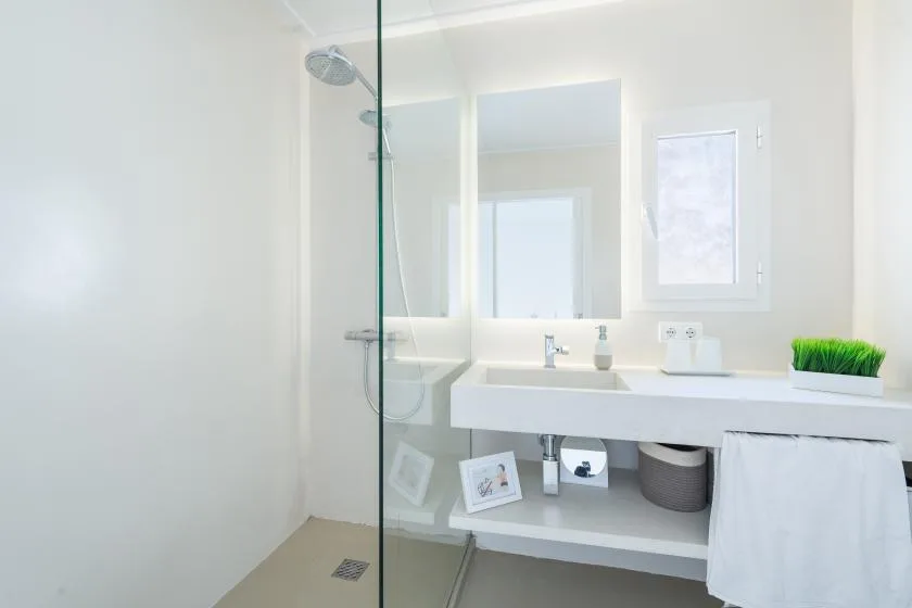 A bright bathroom with a glass shower and a wide sink counter.