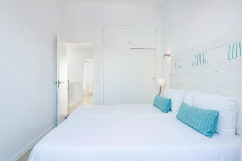 Bedroom with a neatly made bed and turquoise pillows.