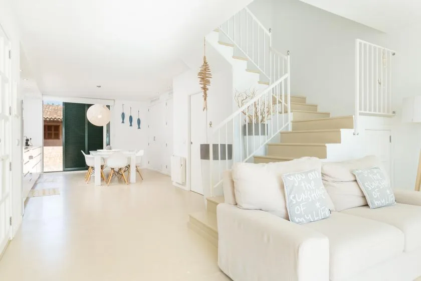 A bright open-plan living and dining area with a staircase and seating.