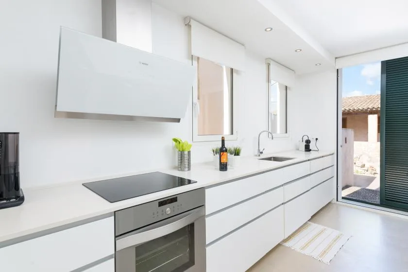 A bright modern kitchen with a long counter, sink, and built-in oven.