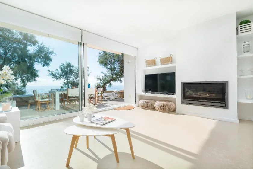 A bright living room with a television and fireplace beside large glass doors.
