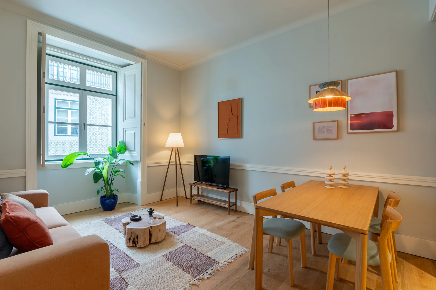 A living and dining room with a television, dining table, and large window.