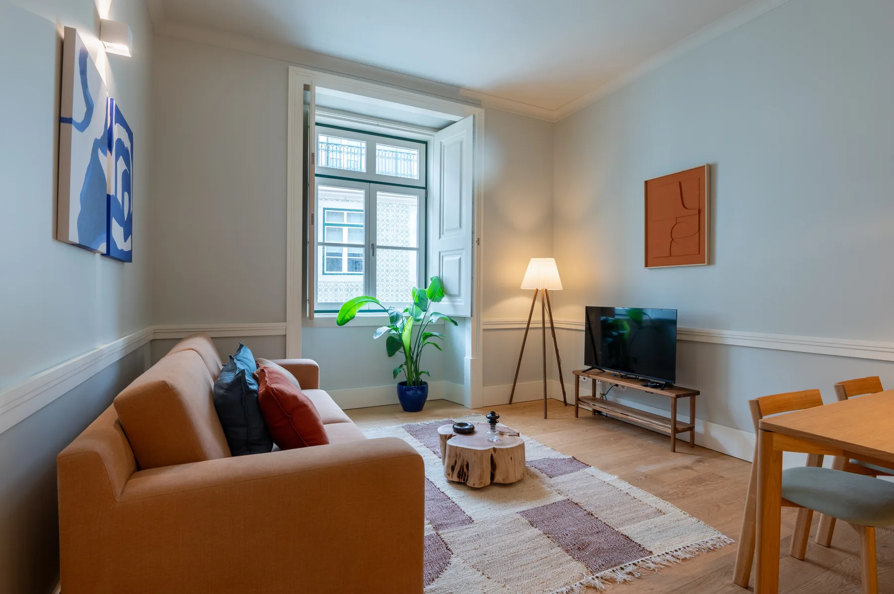 Sala de estar con asientos, un televisor y una ventana grande.
