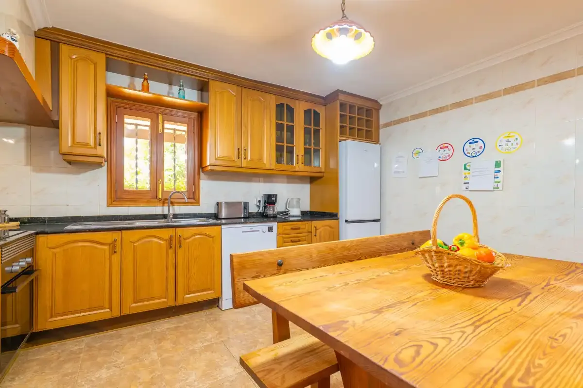 A kitchen with wooden cabinets, a refrigerator, and a large wooden table.