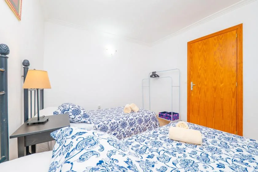 A bedroom with beds covered in blue-and-white patterned bedding and a wooden door.