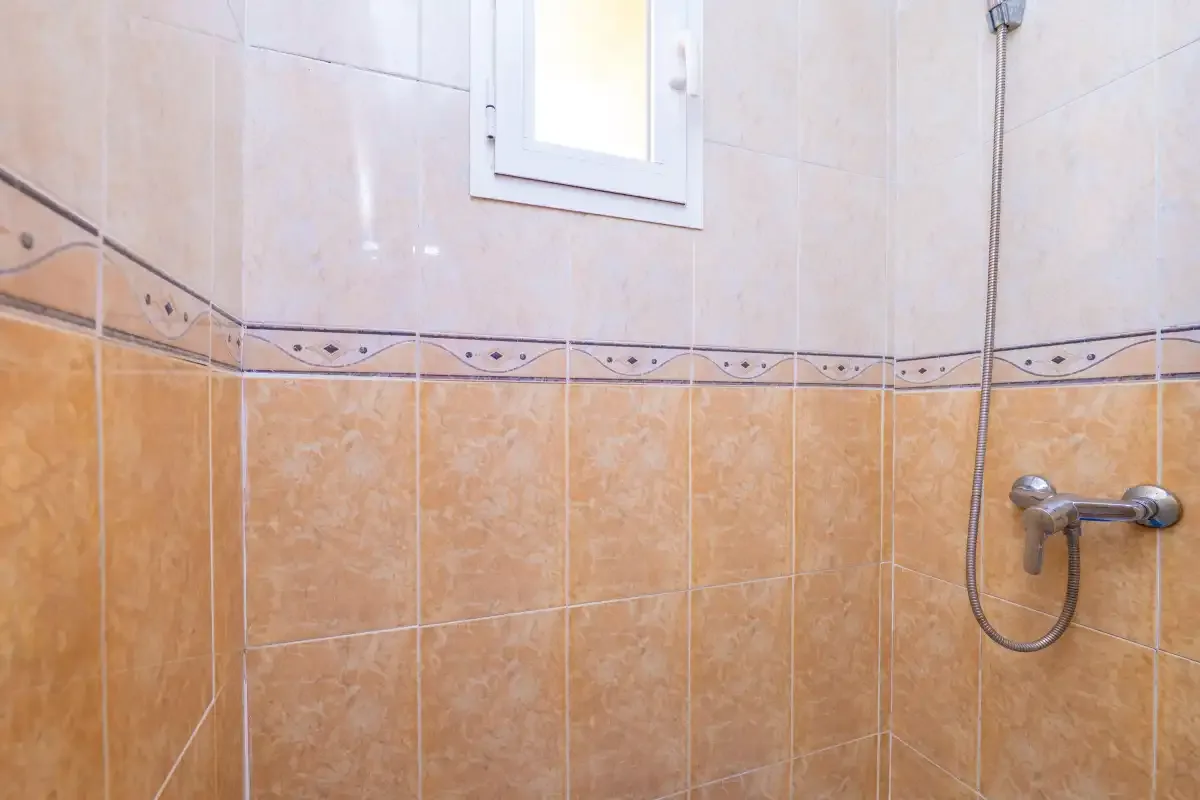 A tiled bathroom shower area with a small window.