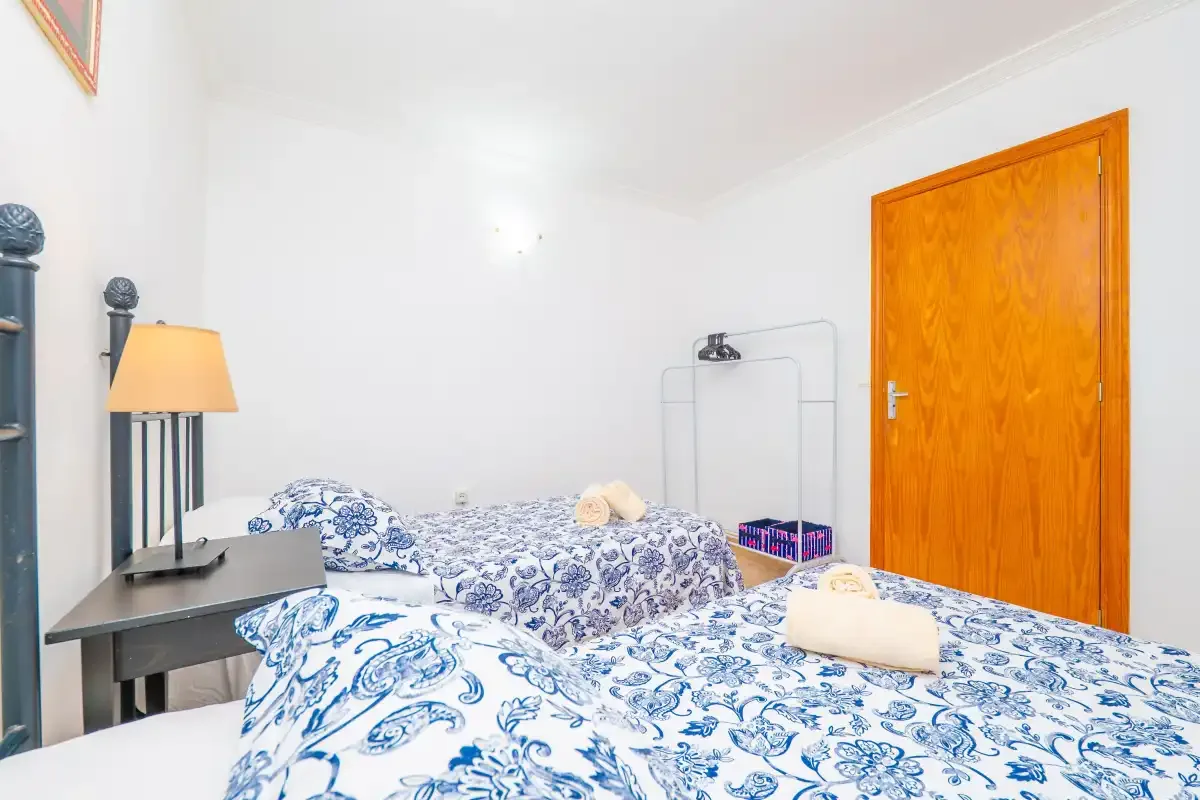 A bedroom with beds covered in blue and white patterned bedding.