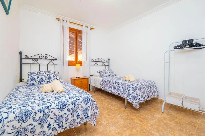 A twin bedroom with two beds covered in blue floral bedding.