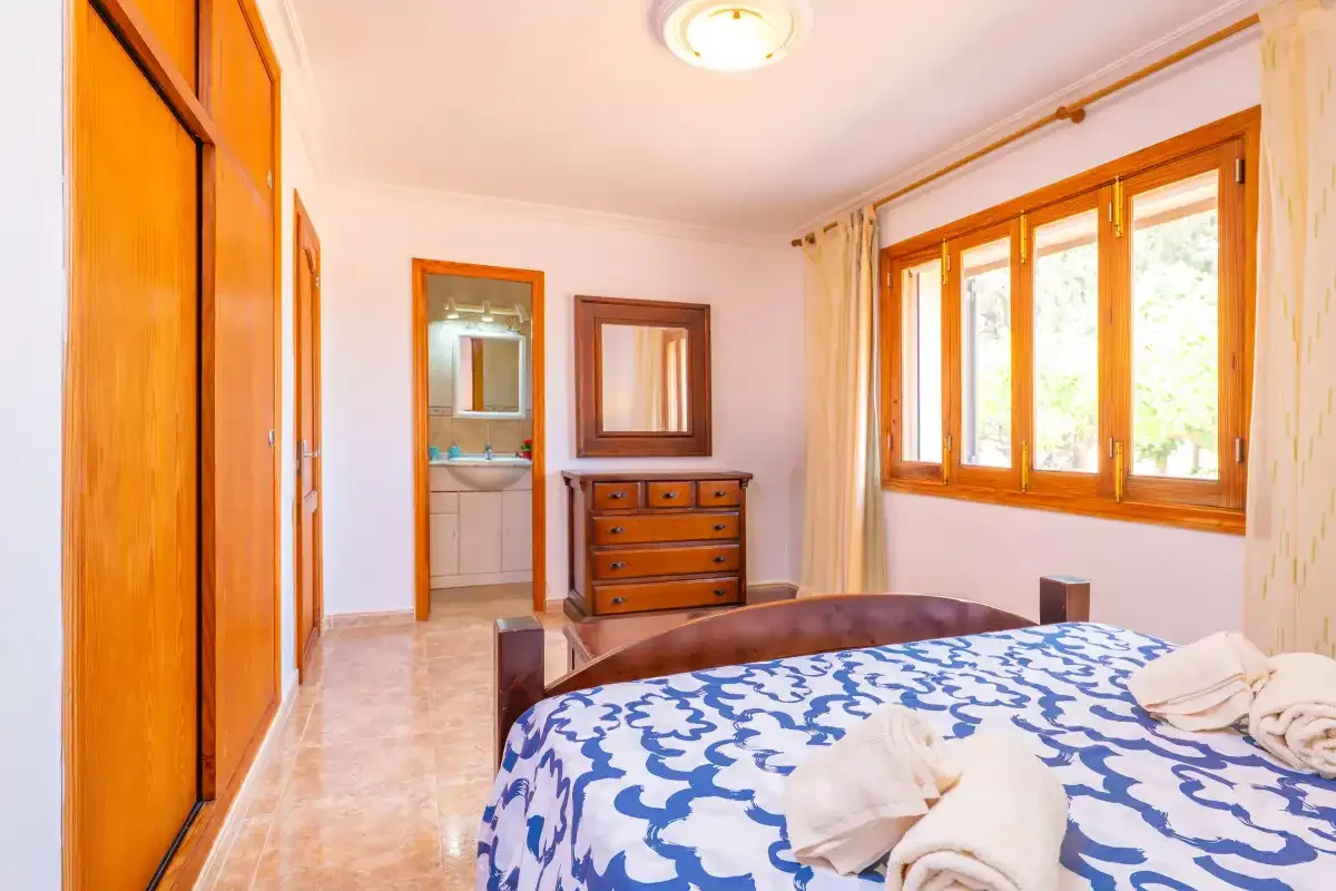A bedroom with a bed covered in blue-and-white patterned bedding and a wooden dresser.