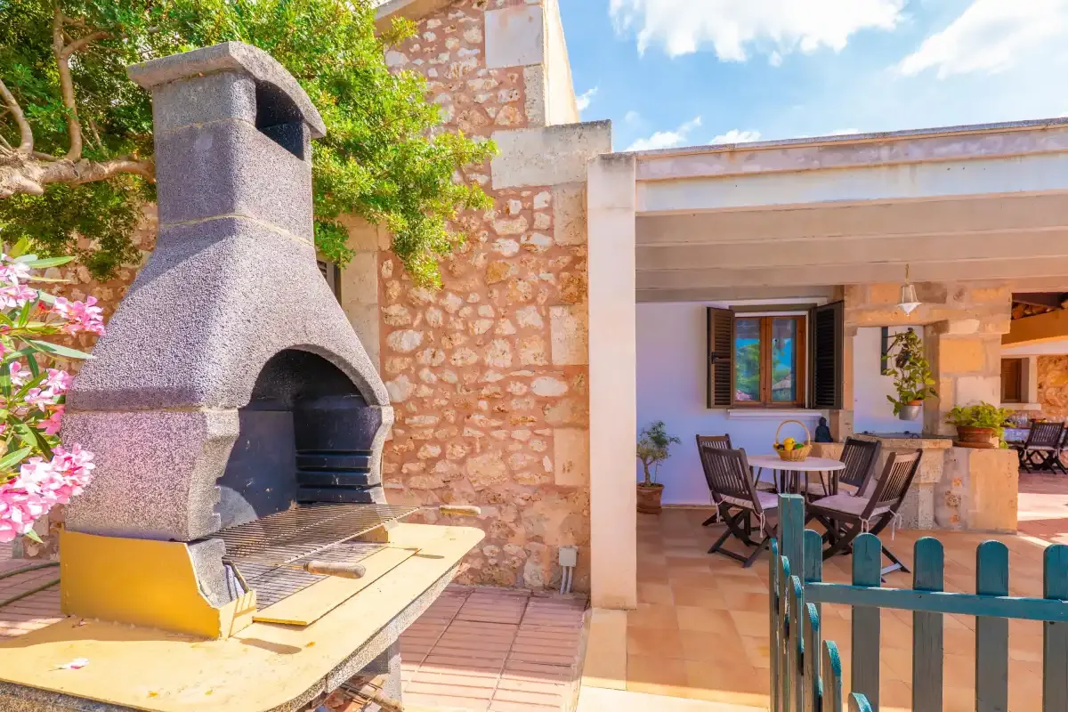 A covered patio with a dining table and a built-in barbecue.