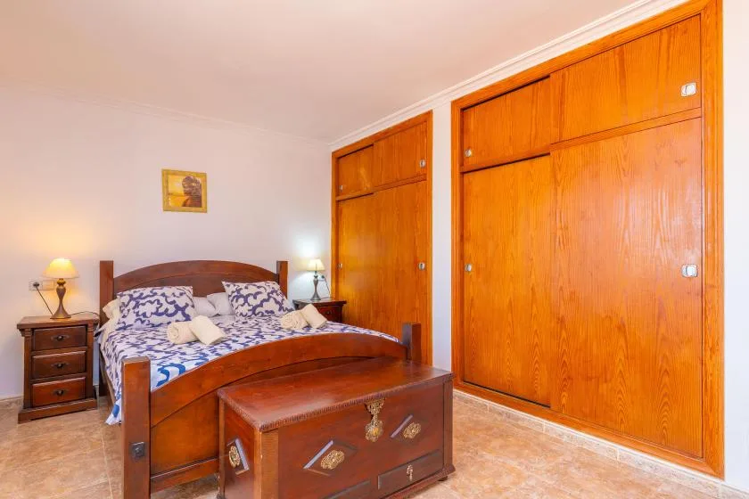 A bedroom with a wooden bed, patterned bedding, and large wooden wardrobes.