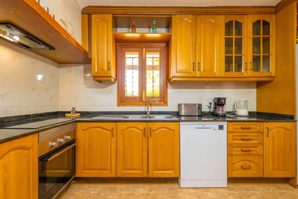 A kitchen with wooden cabinets, a countertop, and a window above the sink.