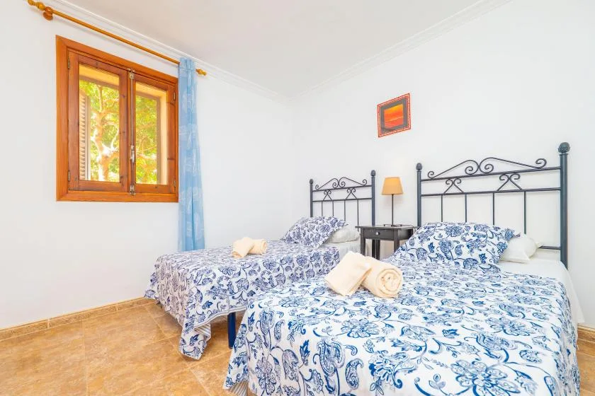 A bright bedroom with two beds dressed in blue-and-white patterned bedding.