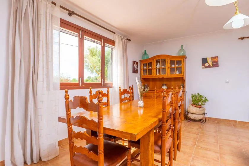 A dining room with a long wooden table beside a large window.