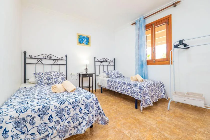A bright bedroom with two beds dressed in blue-and-white patterned bedding.