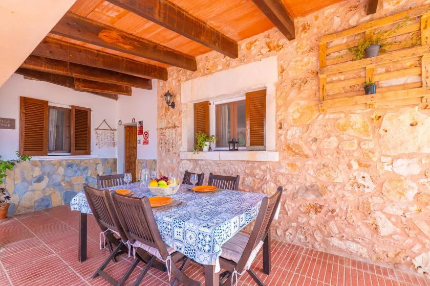 A dining area with a patterned table and wooden ceiling beams.