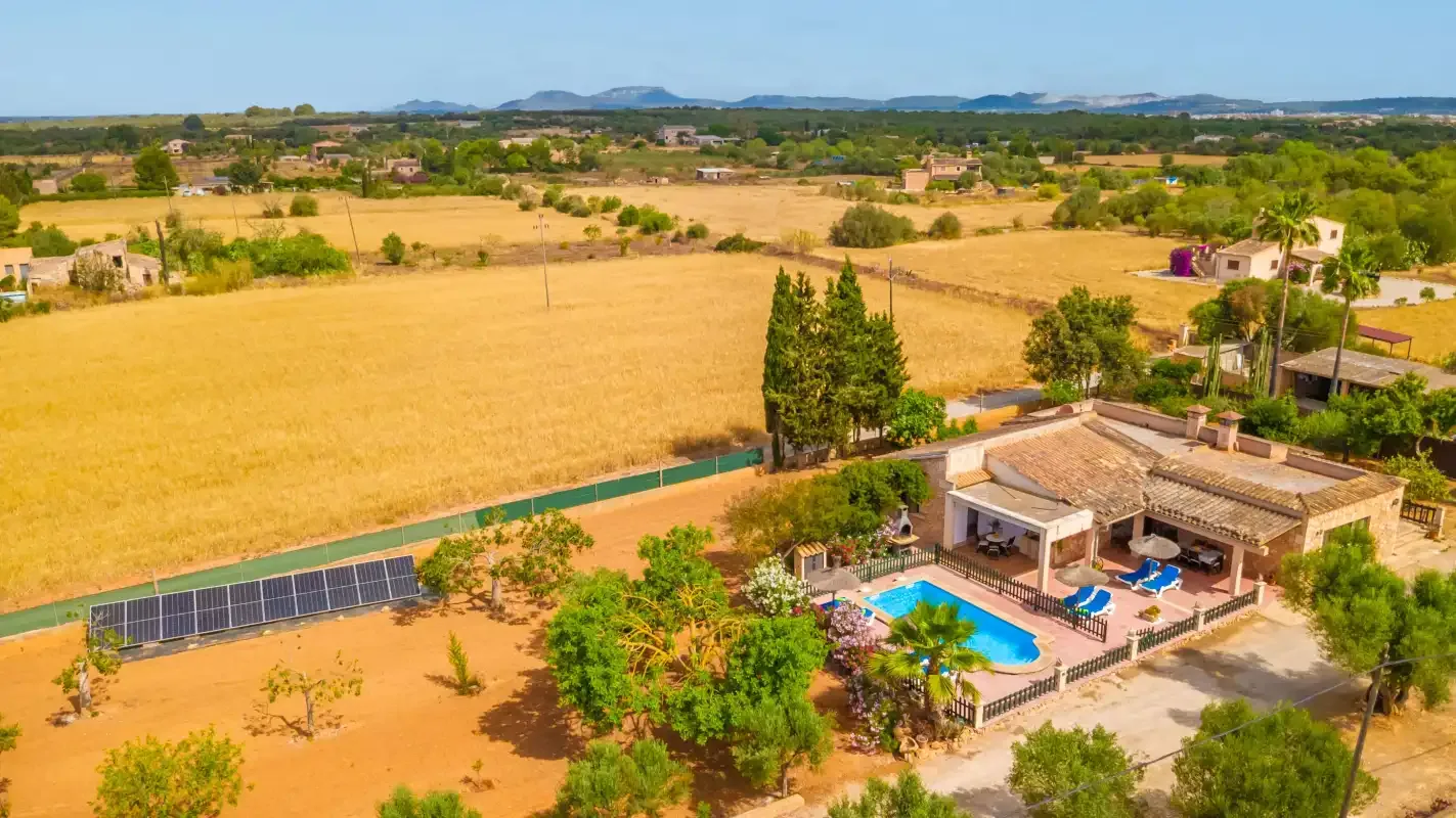 Aerial view of a house and pool beside open fields.